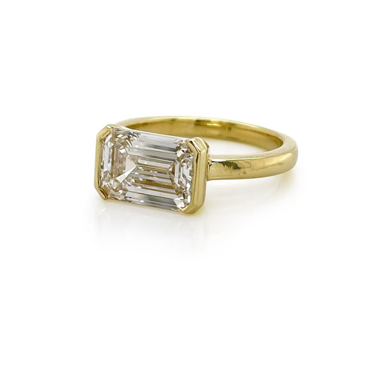 East-west half-bezel emerald cut diamond engagement ring in yellow gold